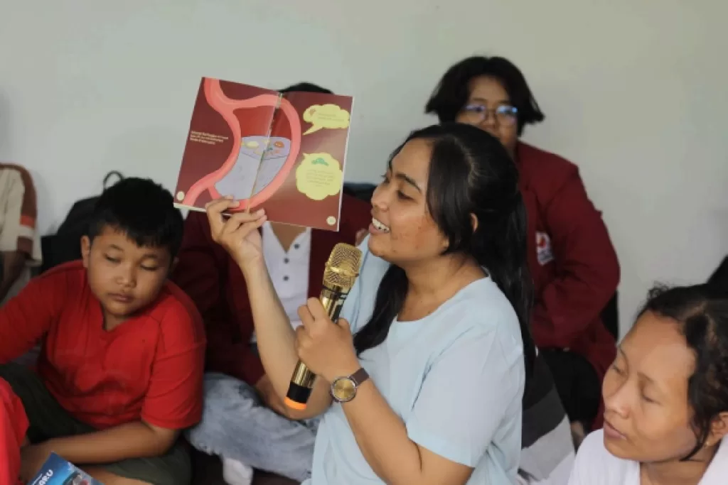 Zeni Natalya memperkenalkan salah satu buku Adya kepada anak-anak di rumah belajar Rotary. (ist)